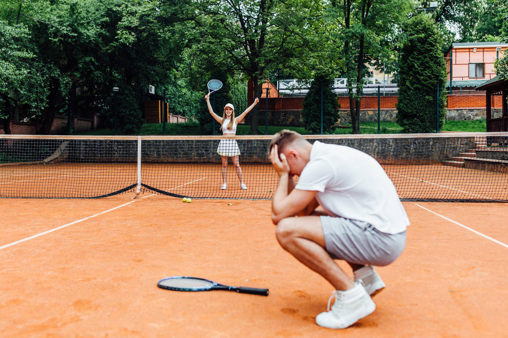 νεαρό ζευγάρι παίζει τένις παιχνίδι υπαίθριο, ο άνθρωπος χάνει   - Φωτογραφία, εικόνα