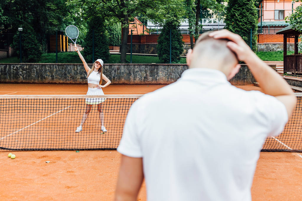 Χαμογελαστός ζευγάρι παίζουν τένις παιχνίδι υπαίθριος άνθρωπος χάνοντας το παιχνίδι   - Φωτογραφία, εικόνα
