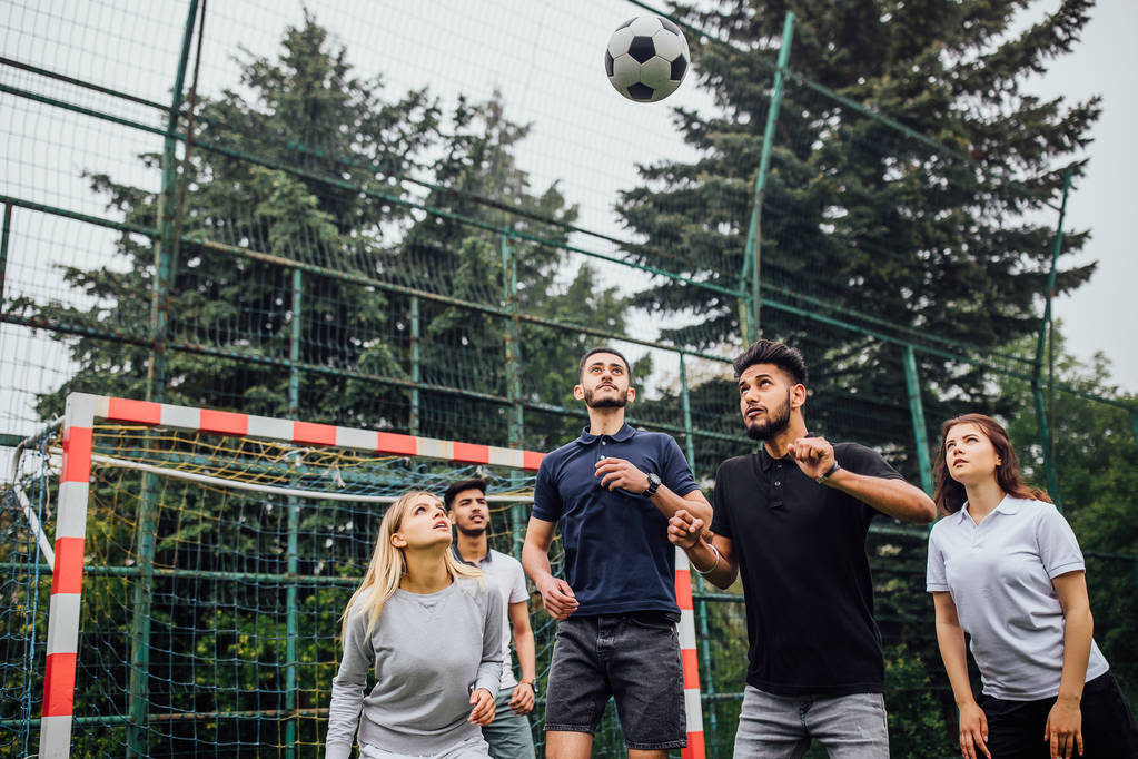 Молодые мужчины и женщины играют в футбол на открытом воздухе
 - Фото, изображение