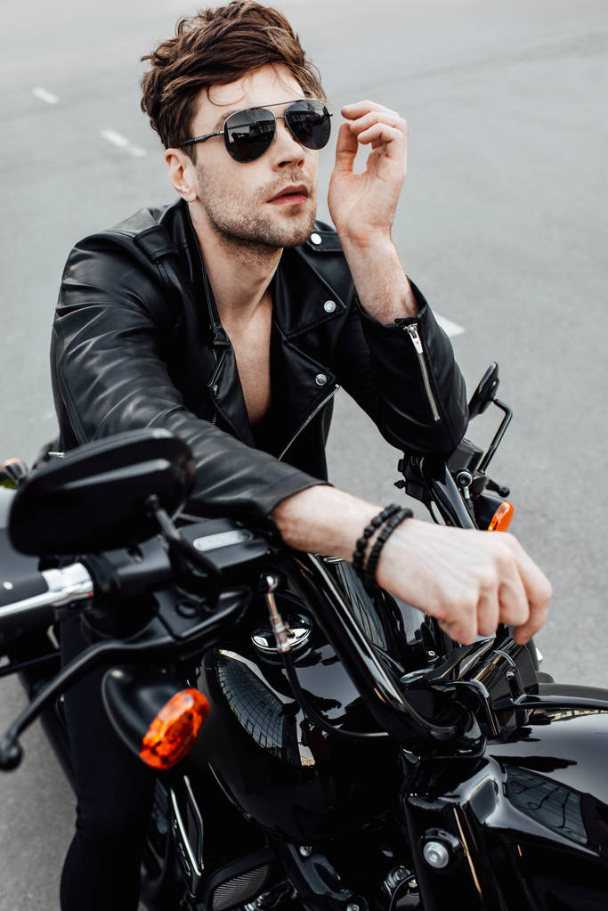 Sexy Mann mit Sonnenbrille sitzt auf Motorrad und freut sich - Foto, Bild