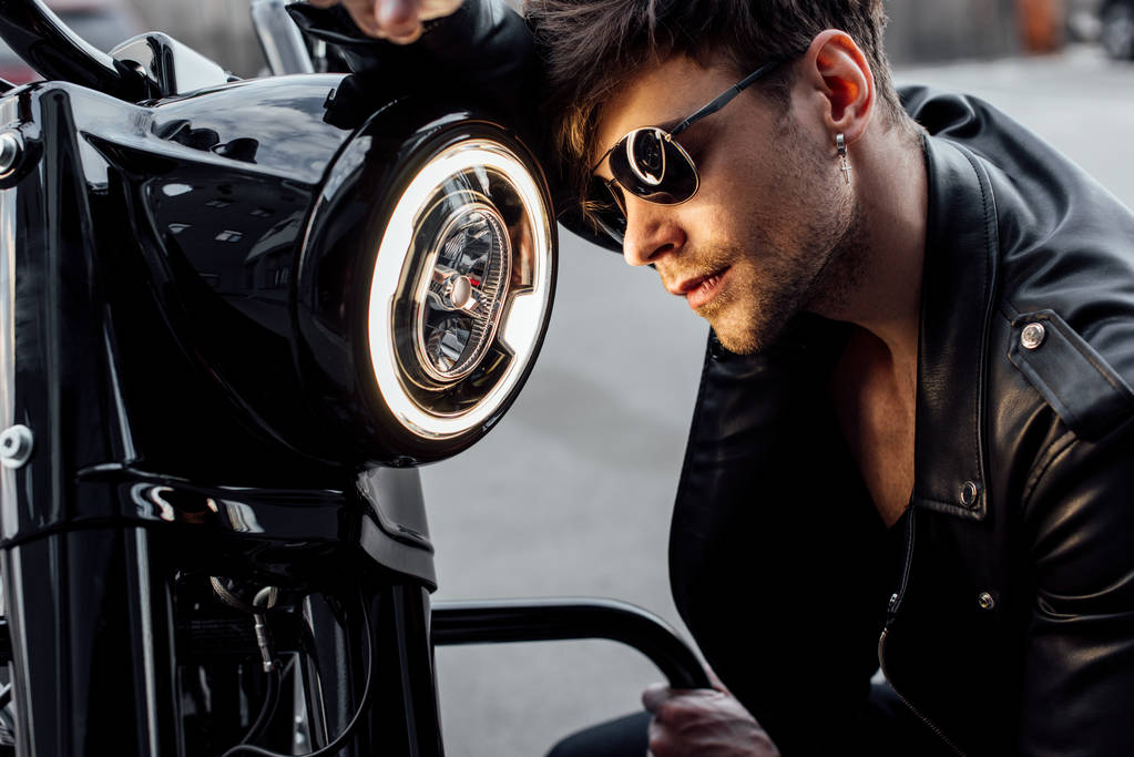 Красивый молодой человек опирается на светящуюся лампу на мотоцикле
 - Фото, изображение