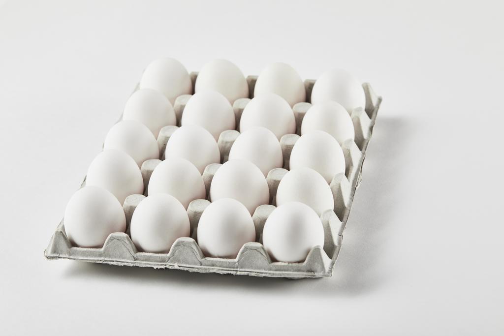 kippen eitjes in kartonnen doos op wit oppervlak - Foto, afbeelding