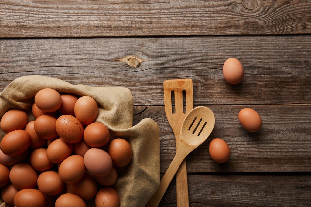  felülnézet csirke tojást ruhával a fa asztal közelében konyhai eszközök - Fotó, kép