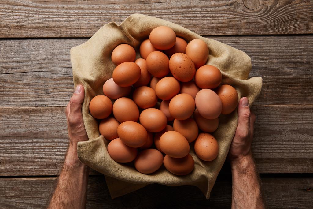  vue du dessus de l'homme tenant des œufs de poulet en tissu sur une table en bois
 - Photo, image