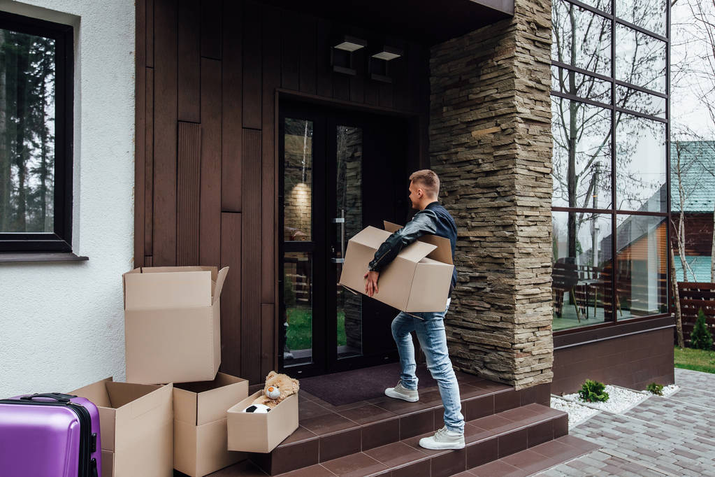 Junger Mann mit Kartons in neuer Wohnung - Foto, Bild