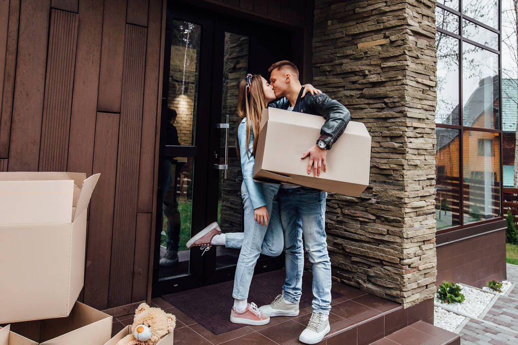 Glückliches Paar küsst sich mit Pappkartons im neuen Haus  - Foto, Bild