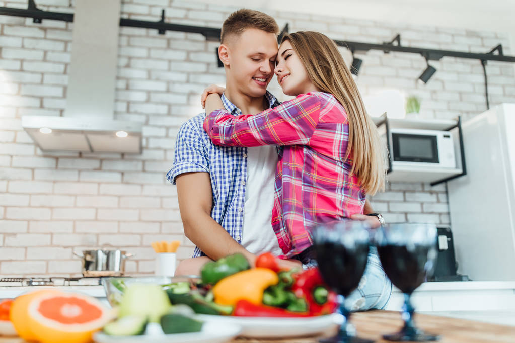 キッチンで抱きしめる幸せな愛するカップルは、前景に焦点を当てます - 写真・画像