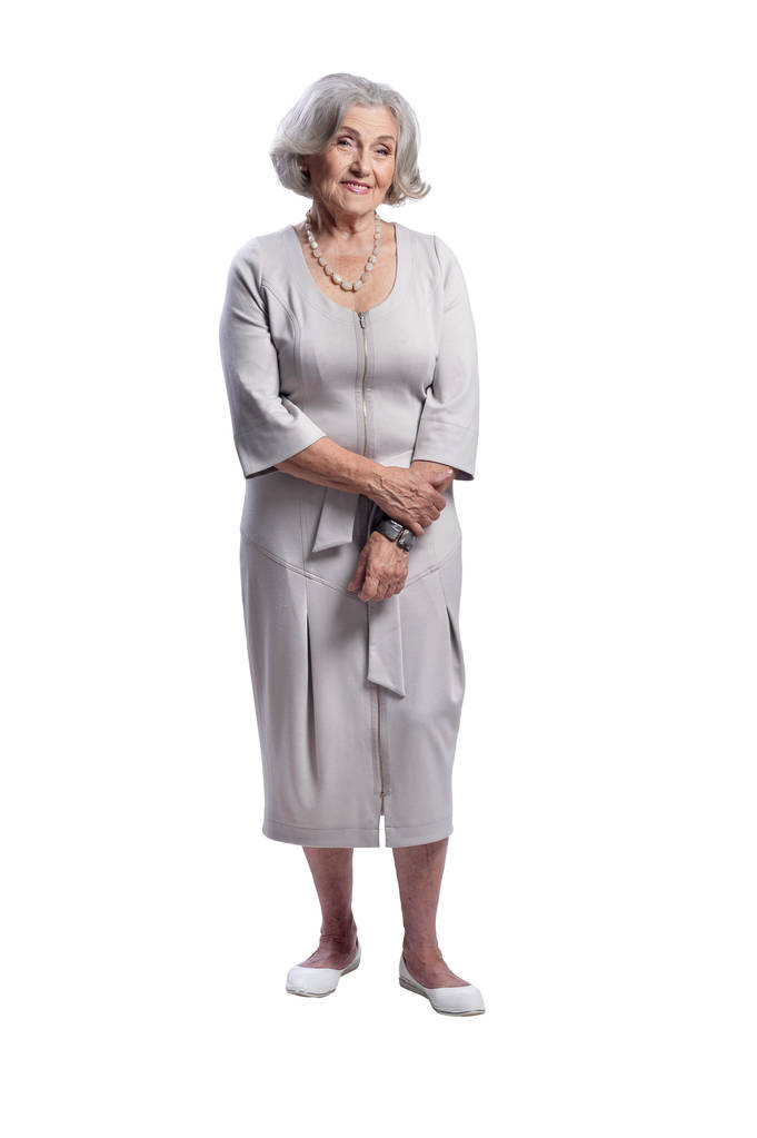 Ευτυχισμένη ανώτερη γυναίκα φορώντας ελαφρύ φόρεμα που παρουσιάζουν απομονωμένη σε λευκό φόντο - Φωτογραφία, εικόνα