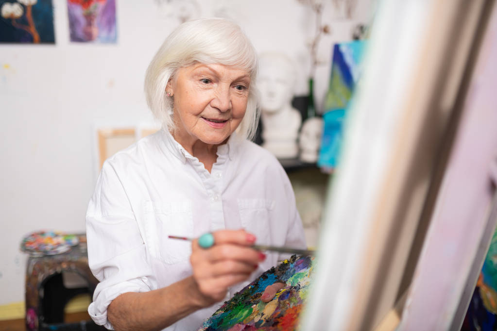 Apelando mulher idosa sorrindo enquanto pintava sobre tela
 - Foto, Imagem