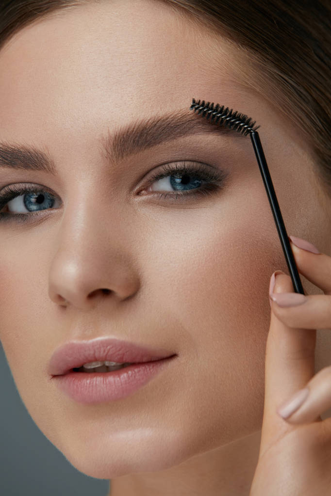 Eyebrow makeup. Woman brushing brows with gel brush closeup - Photo, Image