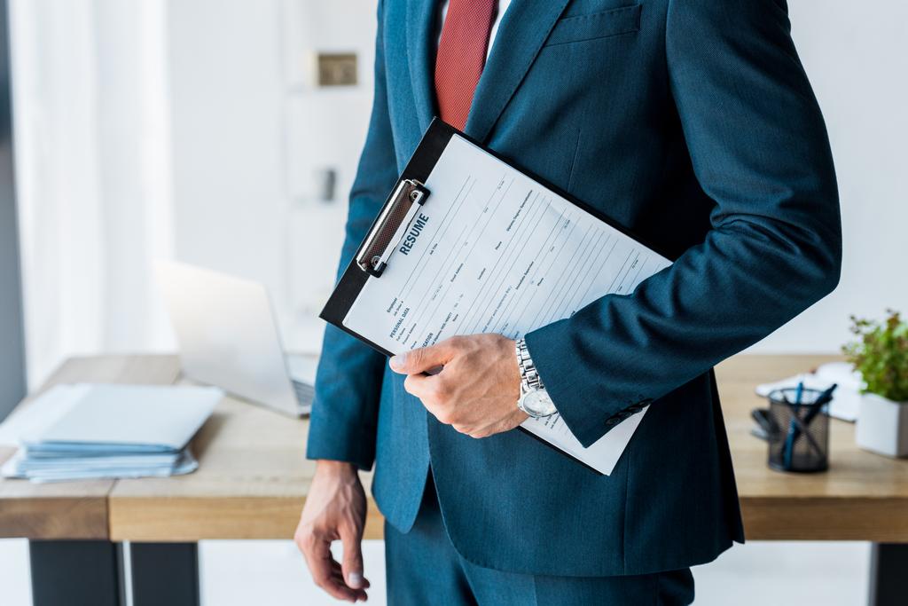 cropped view of recruiter standing and holding clipboard with resume letters  - Photo, Image