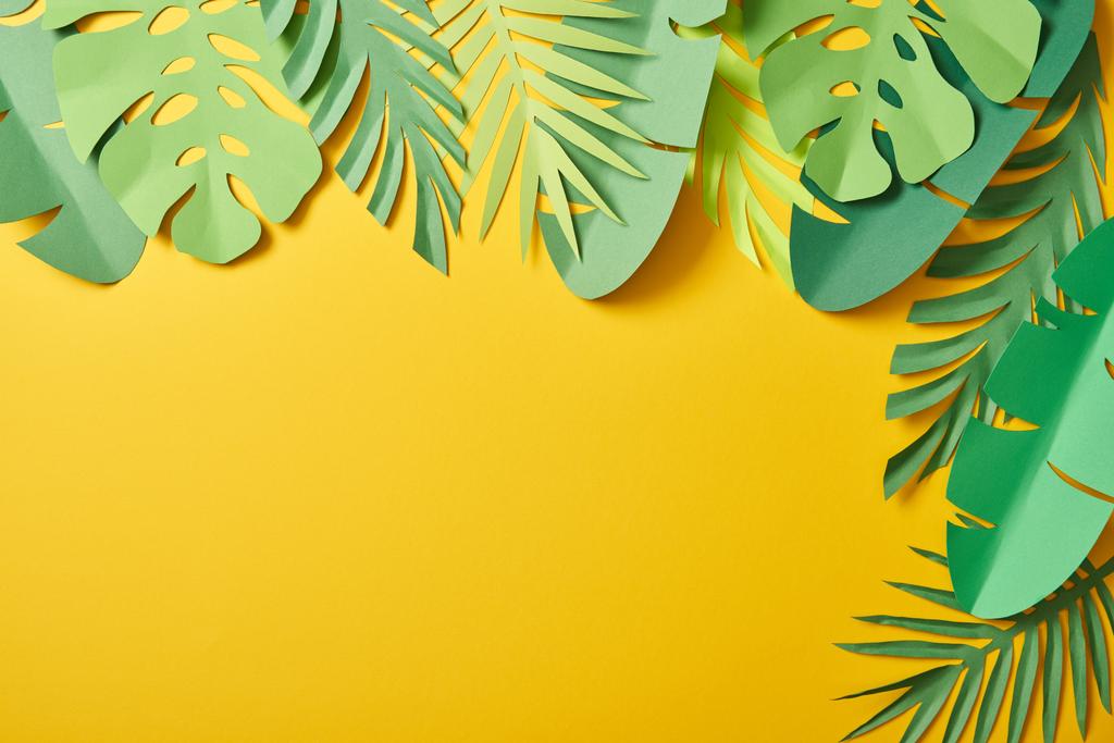 top view of paper cut green palm leaves on yellow background with copy space - Photo, Image