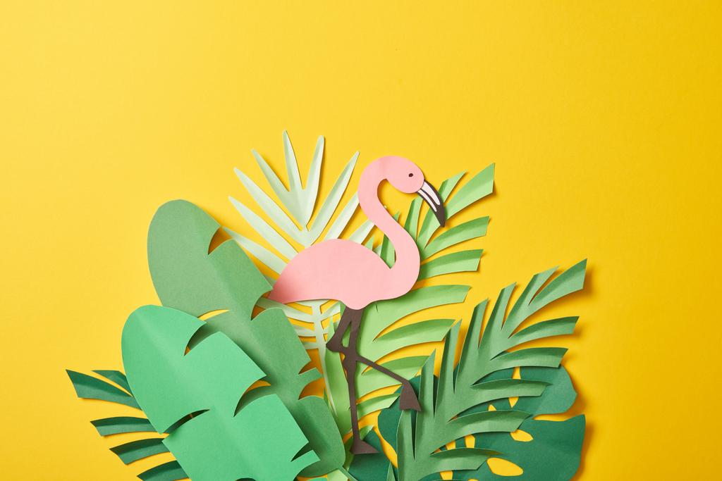 コピースペース付きの黄色の背景に紙カット緑のヤシの葉とピンクのフラミンゴのトップビュー - 写真・画像