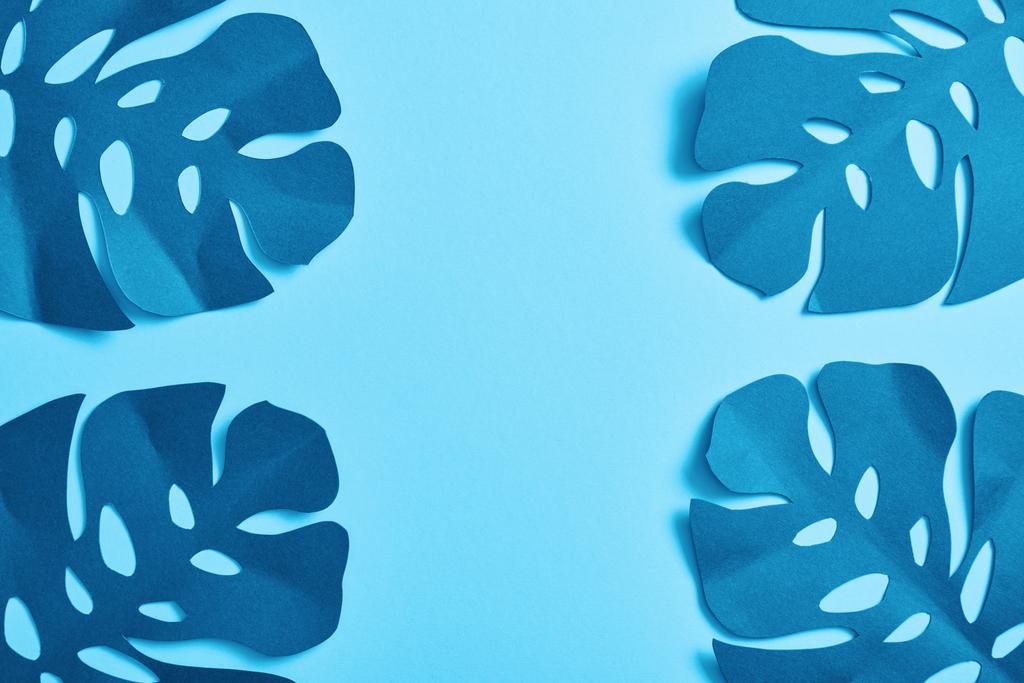 Κορυφαία θέα του μπλε μινιμαλιστικό χαρτί κομμένα φύλλα παλάμης σε μπλε φόντο με χώρο αντιγραφής - Φωτογραφία, εικόνα