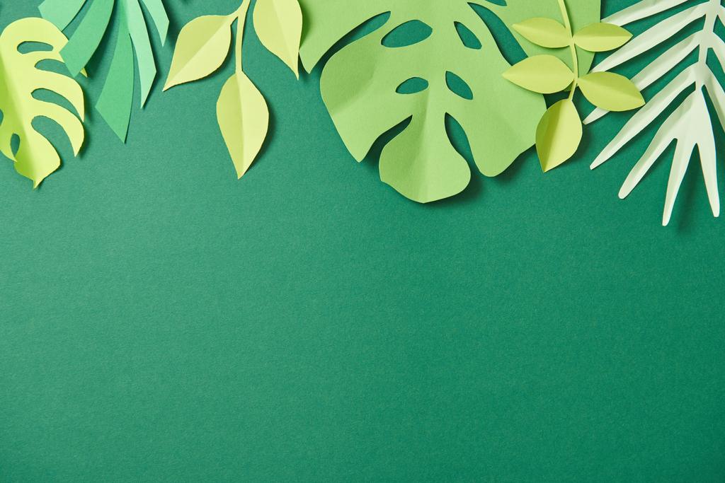 top view of exotic paper cut palm leaves on green background with copy space - Photo, Image