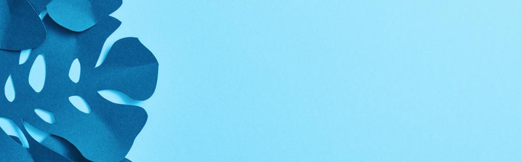 Draufsicht auf blaues exotisches Papier geschnittene Palmblätter auf blauem Hintergrund mit Kopierraum, Panoramaaufnahme - Foto, Bild