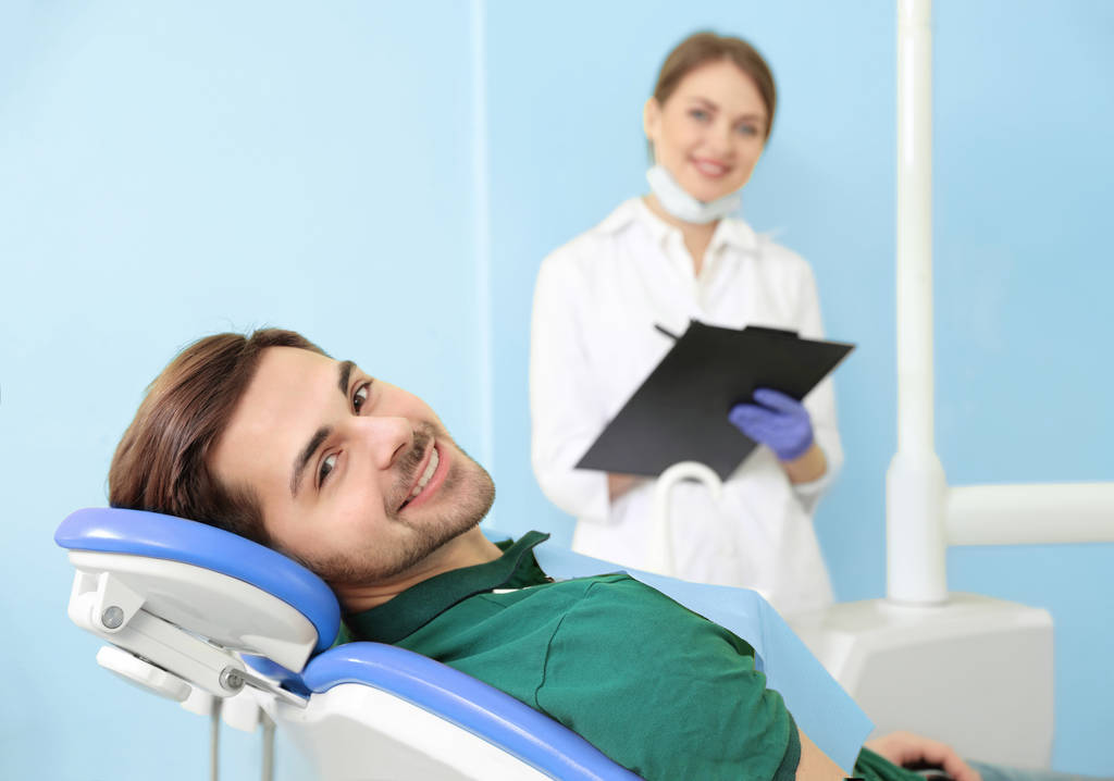 Gelukkige patiënt en tandarts in de moderne kliniek, ruimte voor tekst - Foto, afbeelding