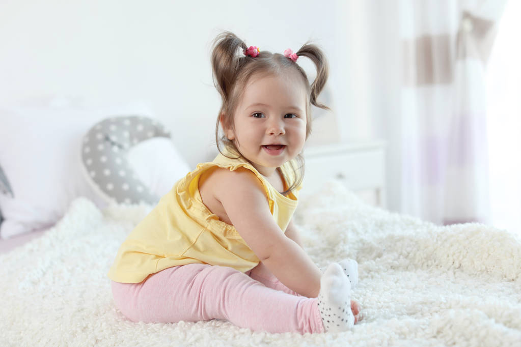 entzückendes kleines Mädchen sitzt auf dem Bett im Zimmer - Foto, Bild