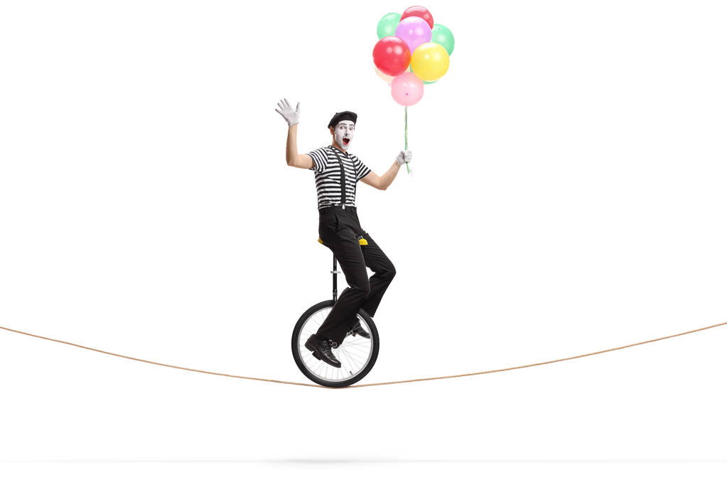 Mime chevauchant un monocycle sur une corde, tenant un tas de ba coloré
 - Photo, image