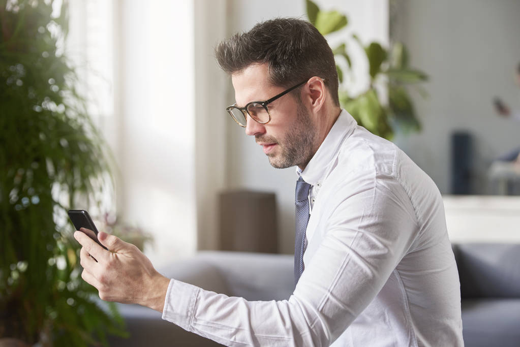 Портрет бизнесмена с помощью мобильного телефона и текстовых сообщений, сидящего в офисе
.  - Фото, изображение