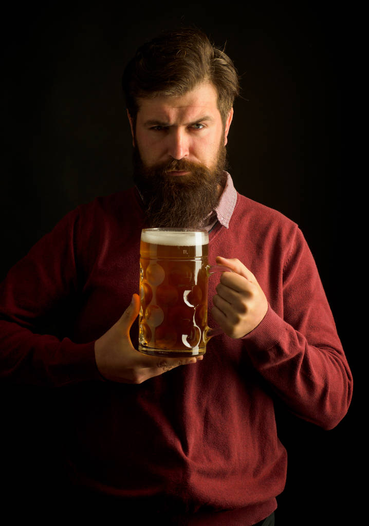 Το πορτραίτο ενός όμορφου νεαρού άντρα που γεύεται μια βαρελίσια μπίρα. Κομψός όμορφος άντρας με μαύρο κουστούμι που πίνει μπύρα πάνω από το μαύρο φόντο. Συναισθηματική αστείο μούσι μεθυσμένος χίπστερ κρατά σκάφη Εμφιαλωμένη μπύρα. - Φωτογραφία, εικόνα