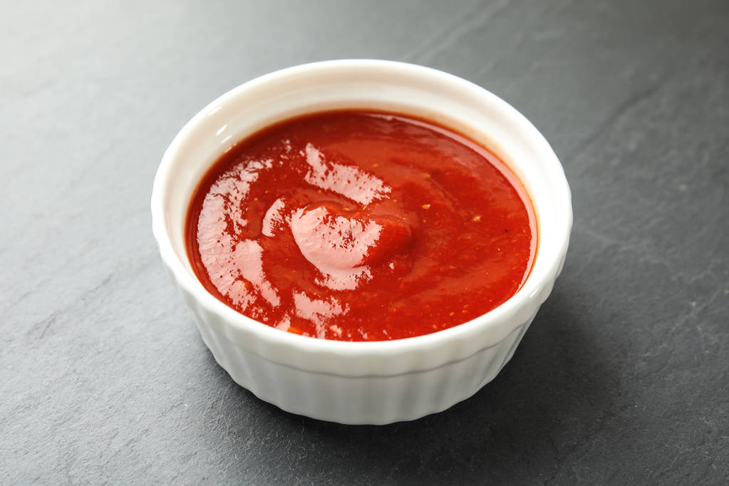 Miska s chutnou rajčatovou omáčkou na šedý stůl - Fotografie, Obrázek