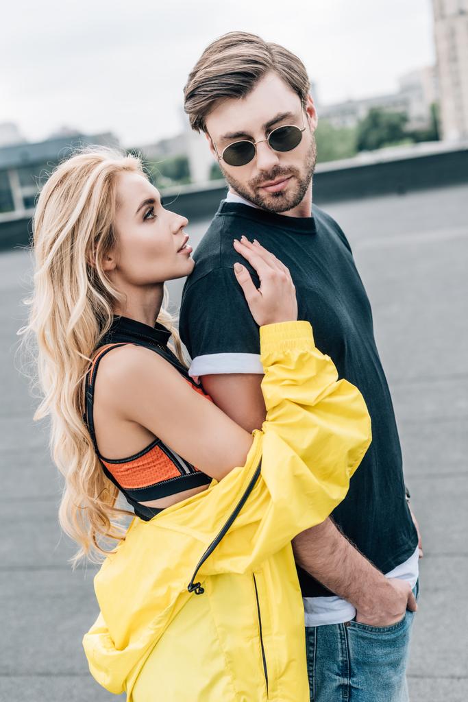 Blonde und attraktive Frau umarmt gutaussehenden Mann mit Brille  - Foto, Bild