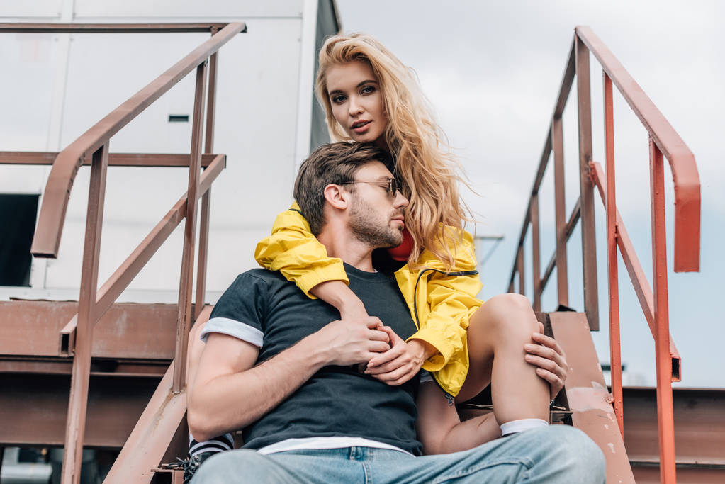 blonde vrouw en knappe man in glazen zittend op trappen  - Foto, afbeelding