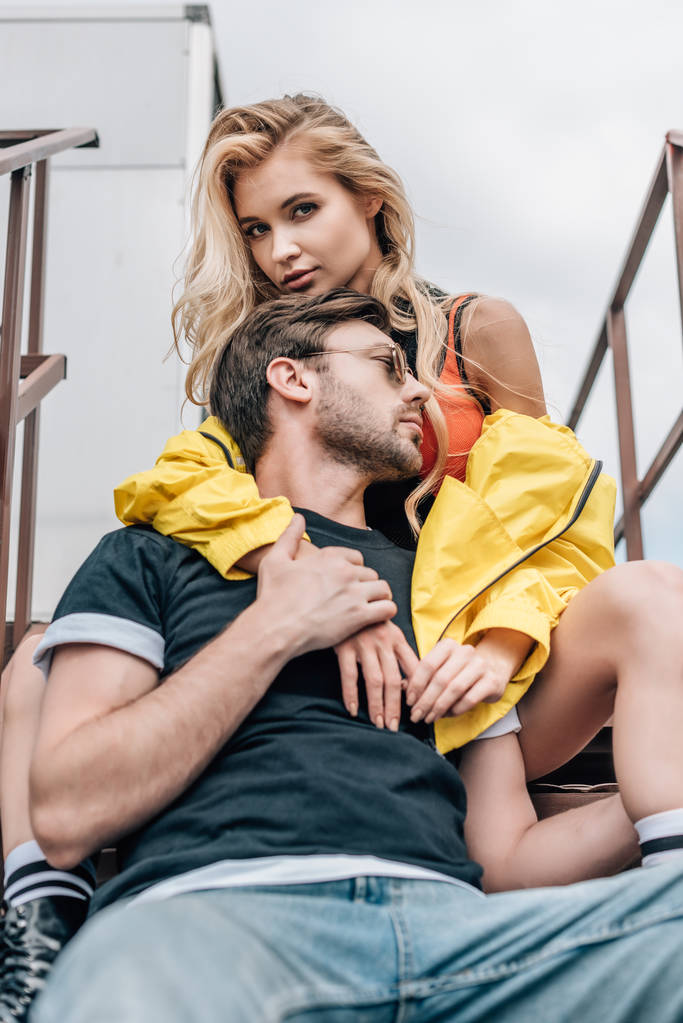 blond kobieta i przystojny mężczyzna w okularach przytulanie na dachu  - Zdjęcie, obraz