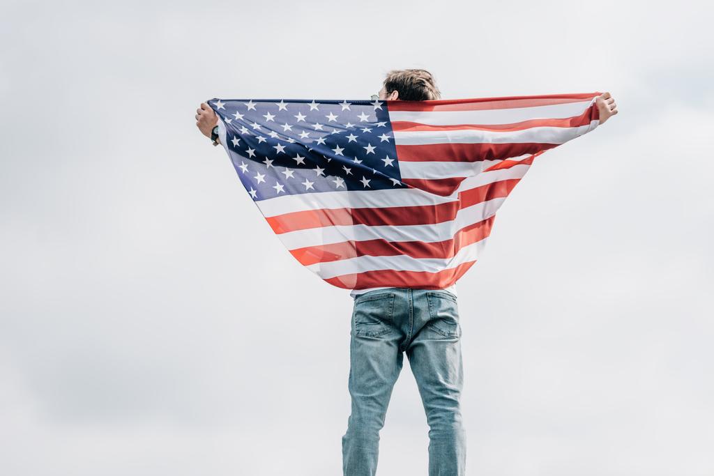 Rückansicht eines Mannes in Jeans mit amerikanischer Flagge auf dem Dach  - Foto, Bild