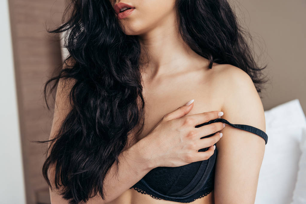 částečný pohled na sexy mladou ženu v černém prádle na posteli - Fotografie, Obrázek