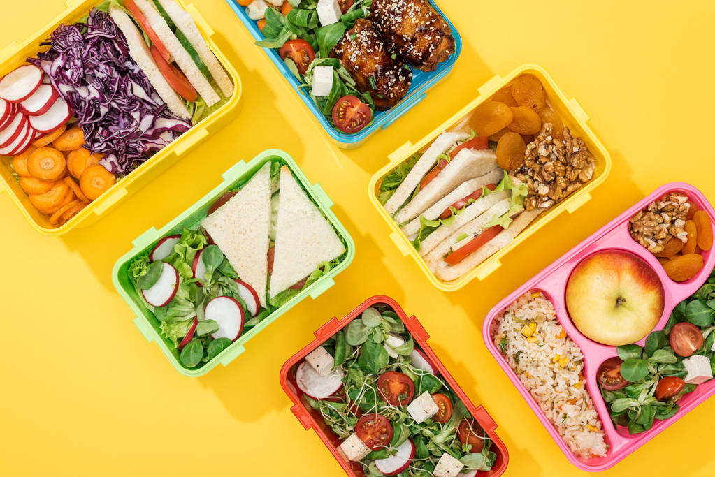 黄色の背景に食べ物を持つ弁当箱のトップビュー - 写真・画像