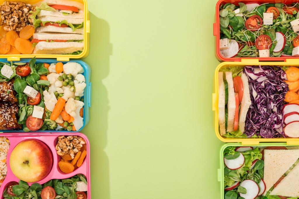 top view of lunch boxes with food on green background with copy space - Photo, Image