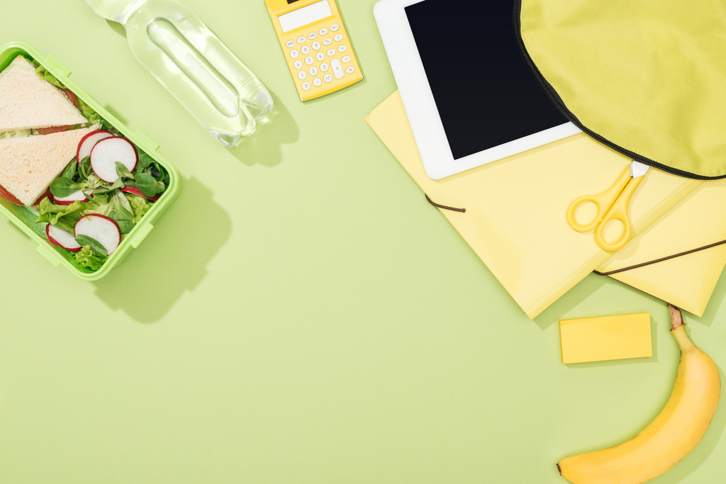 top view of backpack with digital tablet near lunch box, stationery and bottle of water - Photo, Image