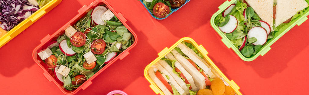 tiro panorâmico de lancheiras com comida no fundo vermelho
 - Foto, Imagem