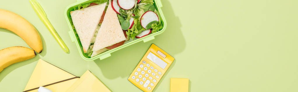 Panoramaaufnahme einer Lunchbox mit Lebensmitteln in der Nähe von Bürobedarf - Foto, Bild