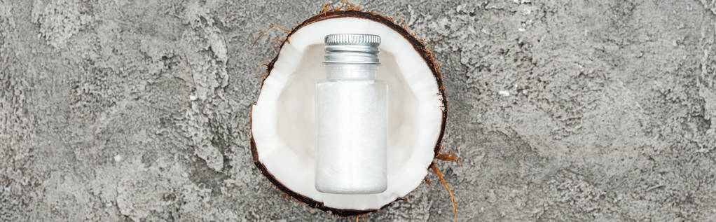 Nejlepší pohled na smetanu v láhvi na kokosové půlce na šedém pozadí, panoramatický záběr - Fotografie, Obrázek