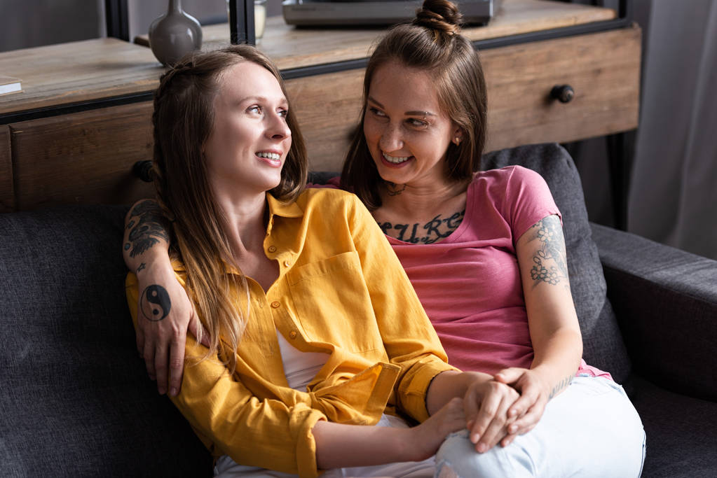 deux jolies lesbiennes embrassant tout en étant assis sur le canapé dans le salon
 - Photo, image