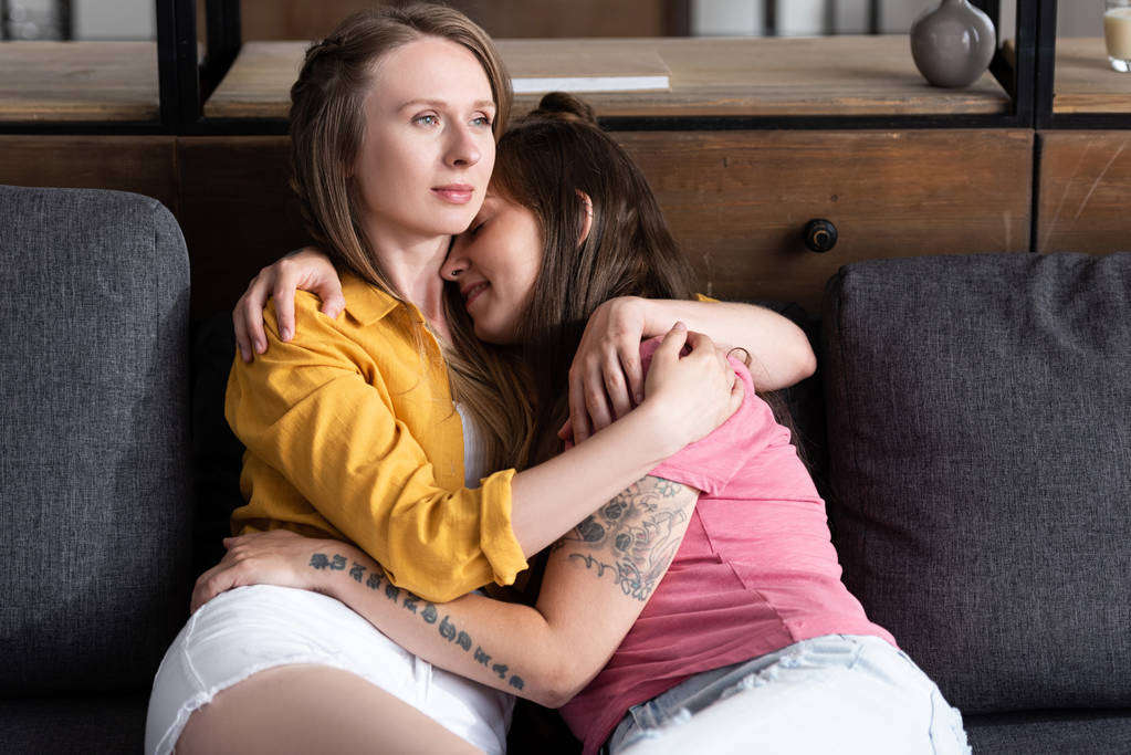 dvě hezká lesbičky, kteří sedí na pohovce v obývacím pokoji - Fotografie, Obrázek