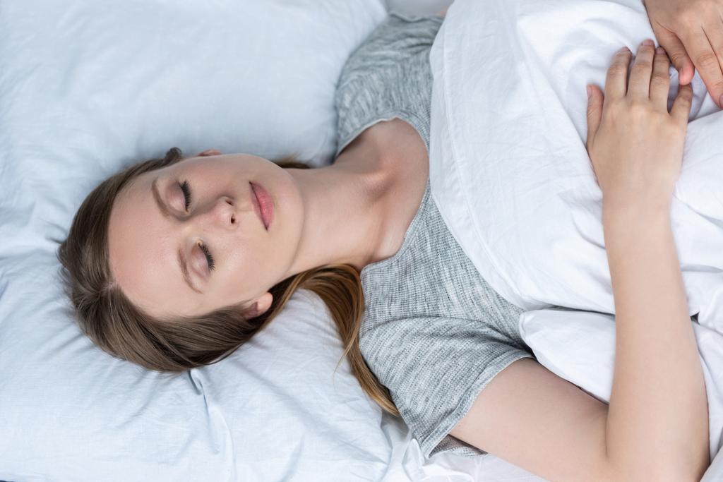 pohled shora mladé ženy spí v posteli pod dekou - Fotografie, Obrázek