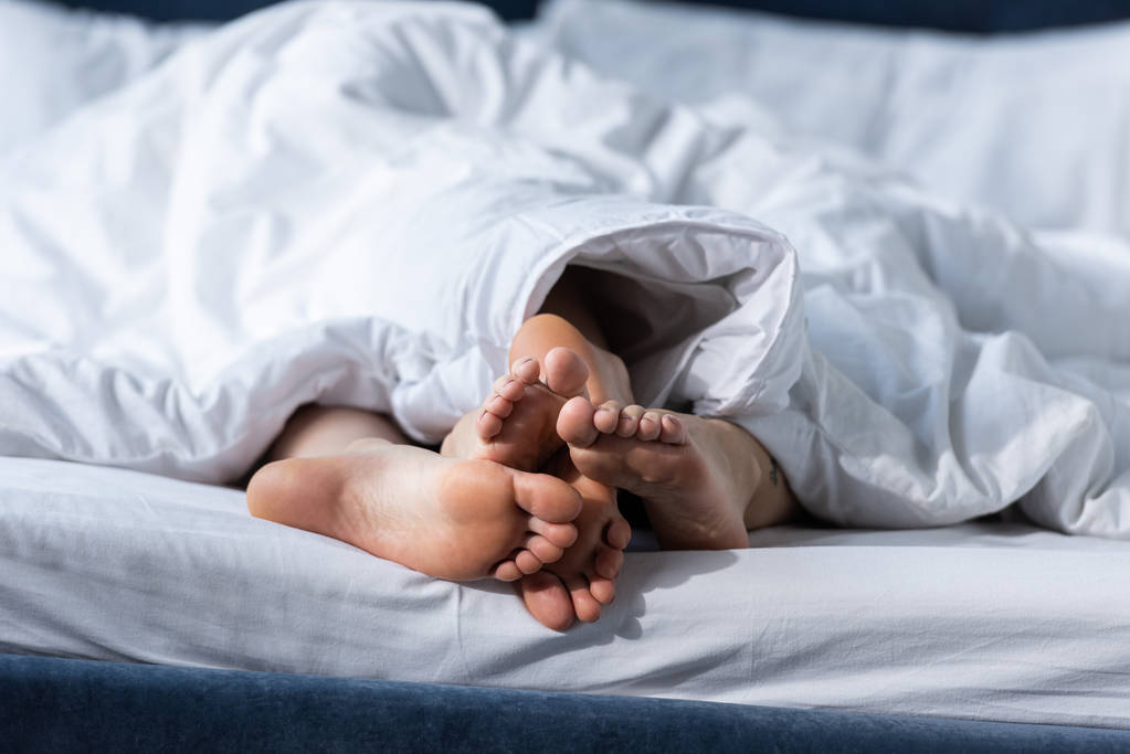 vue partielle de deux lesbiennes pieds nus couchées sous la couverture
 - Photo, image