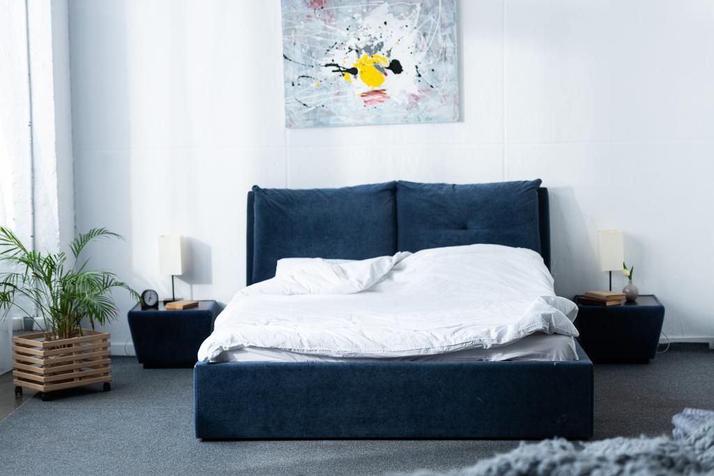 acogedor dormitorio moderno con cama y planta verde
 - Foto, Imagen