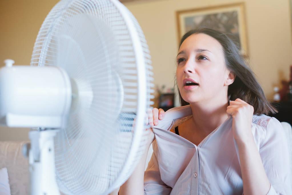 Mädchen vor elektrischem Ventilator versucht sich zu erfrischen - Foto, Bild