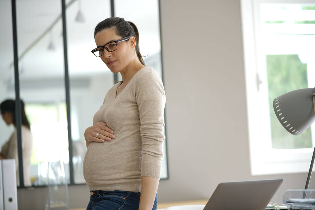 Pregnant businesswoman standing in office - Photo, Image