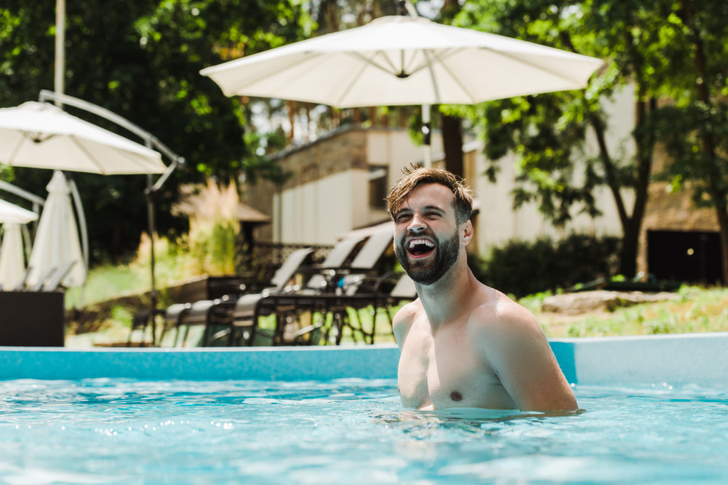 boldog szakállas férfi mosolyogva úszás a medencében  - Fotó, kép