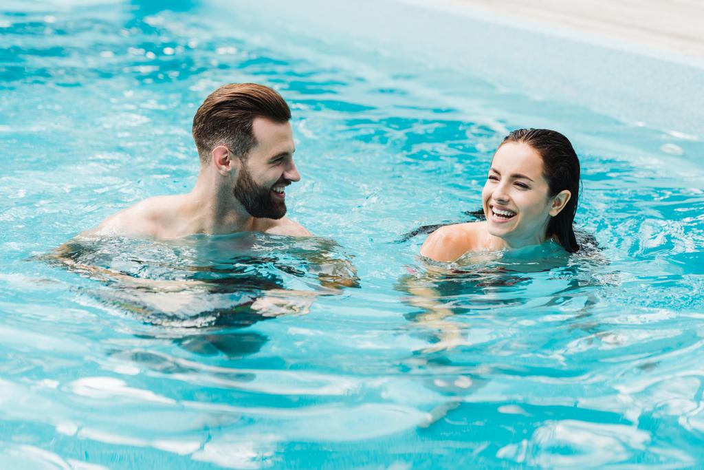 hombre barbudo guapo mirando a mujer atractiva en la piscina
  - Foto, imagen