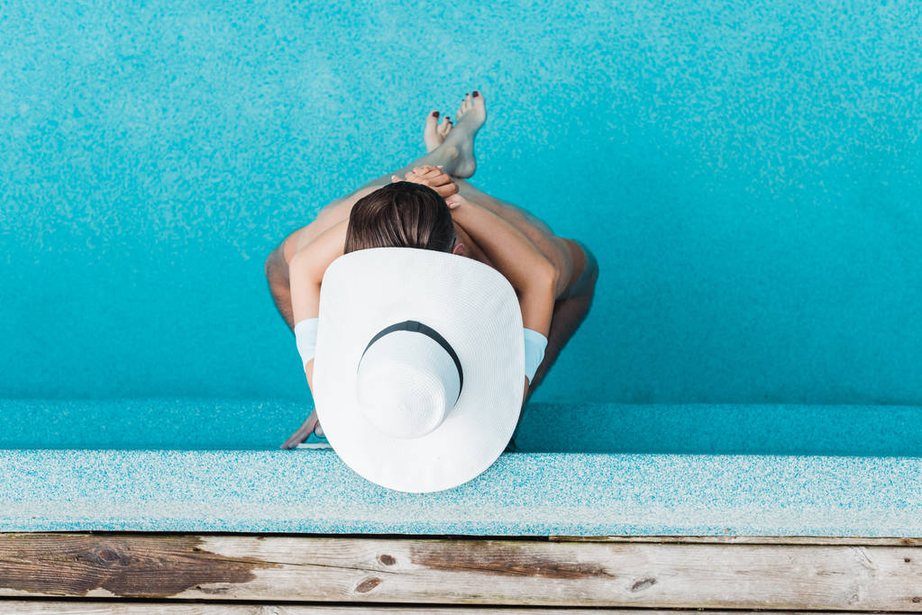 Top uitzicht van vrouw in stro hoed en man in zwembad  - Foto, afbeelding