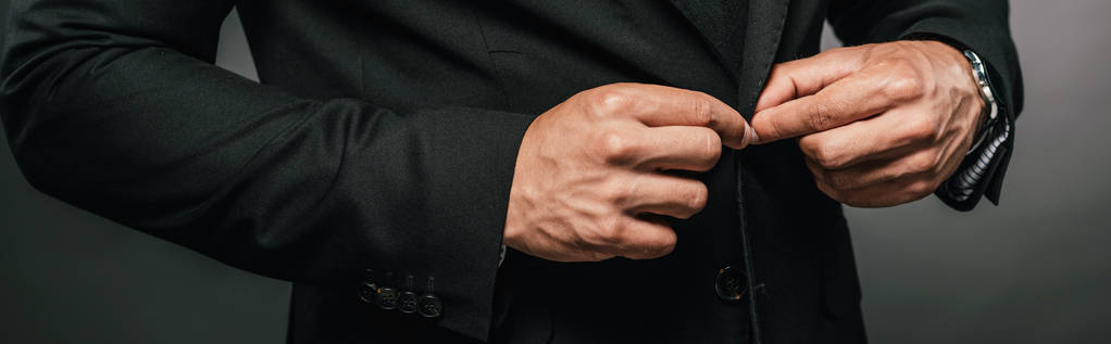 vista ritagliata di uomo d'affari afroamericano in abito pulsante di fissaggio su sfondo scuro, colpo panoramico
 - Foto, immagini
