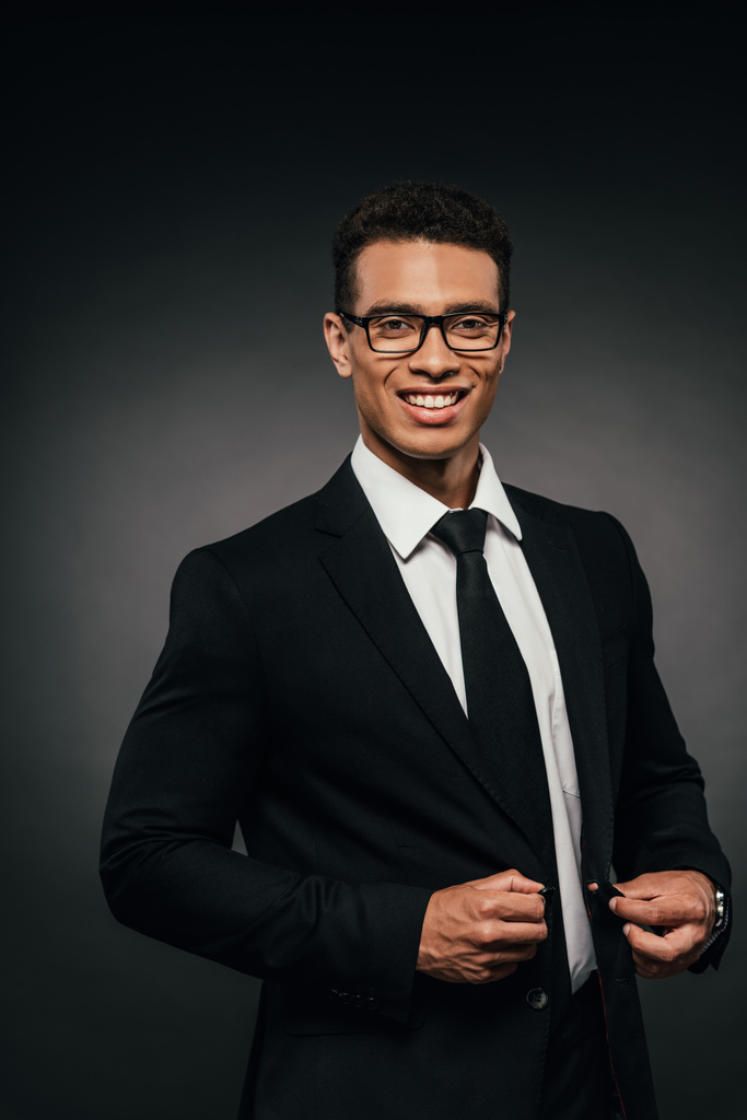przystojny African American biznesmen w okularach i garnitur na ciemnym tle - Zdjęcie, obraz