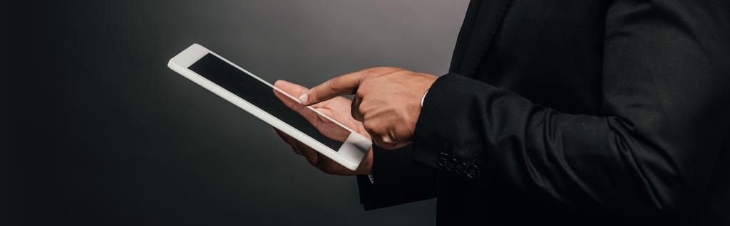 Ausgeschnittene Ansicht eines afrikanisch-amerikanischen Geschäftsmannes mit digitalem Tablet auf dunklem Hintergrund - Foto, Bild